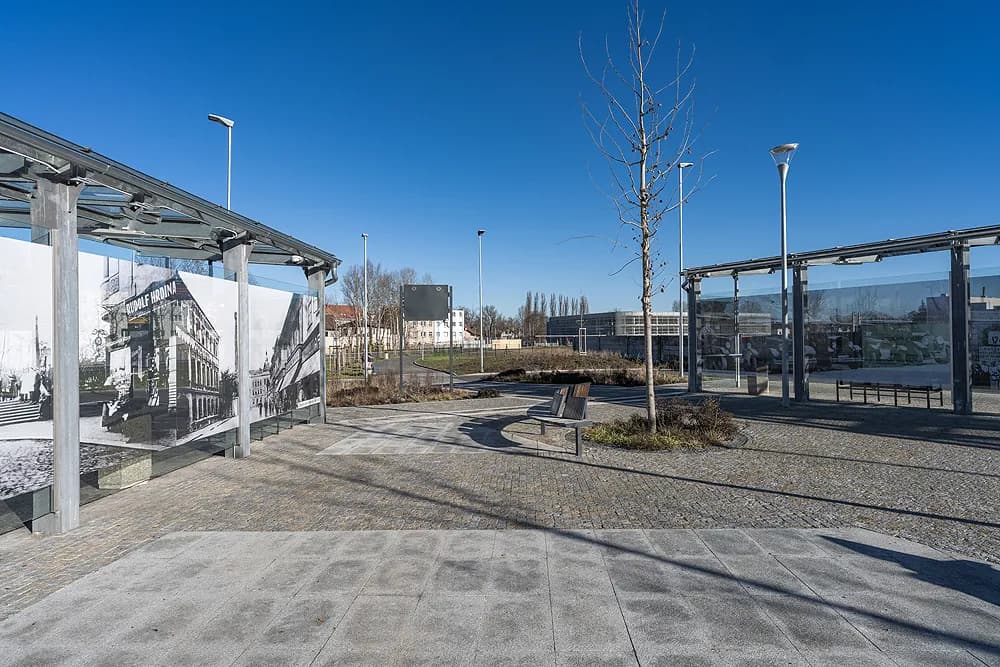 Autobusový terminál v Kralupech nad Vltavou s historickými fotografiemi, žulovou dlažbou, lavičkami a moderním osvětlením.