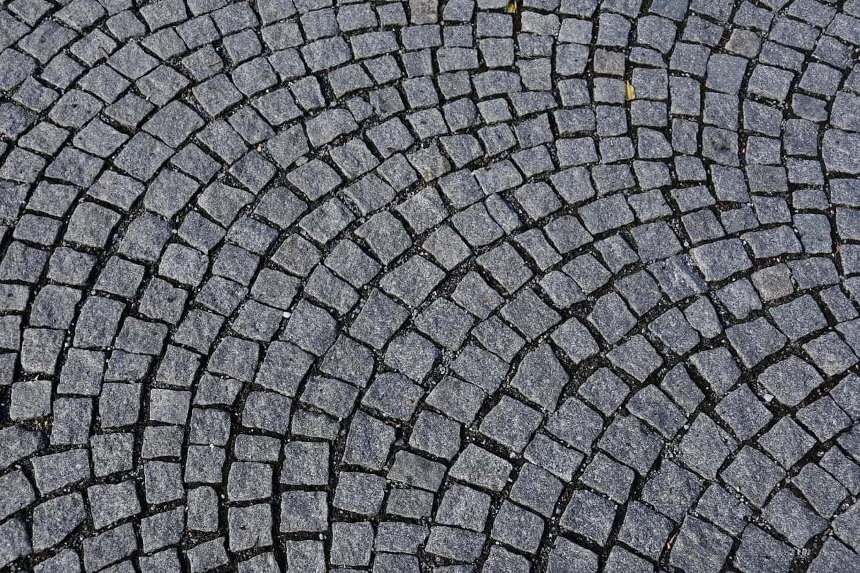 Detail obloukové dlažby z tmavé žulové kostky v Priessnitzových léčebných lázních v Jeseníku.